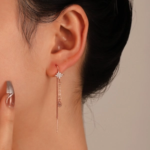 Detail of rose gold tassel earrings featuring a zircon-studded star and dangling snake chains