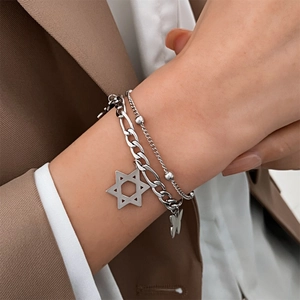 Close-up of double-layer silver chain bracelet with star and butterfly pendants on wrist