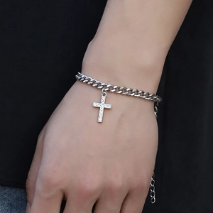 Detailed shot of a silver Cuban link bracelet with a sparkling crystal cross pendant