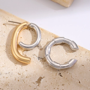 Macro shot of a paperclip stud and C-shaped bamboo earring on a stone surface