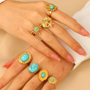 Détail de bagues bohèmes dorées avec pierres turquoise et motifs marins vintage