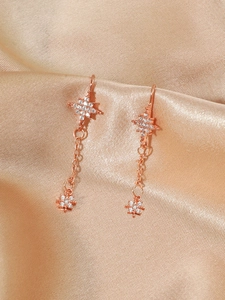 Detail of rose gold tassel earrings with zircon stars on elegant champagne satin