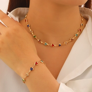 Parure collier et bracelet avec pierres colorées en cœur et chaîne dorée sur chemise