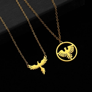 Detail of two-piece golden eagle pendants on fine chains over a textured black backdrop