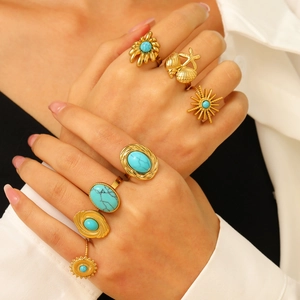 Détail de bagues bohèmes dorées avec pierres turquoises portées par un mannequin en style rétro