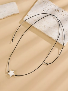 Close-up of minimalist silver star pendant necklace on rustic stone with soft shadow