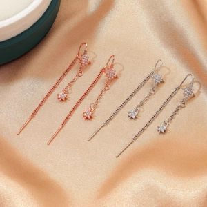 Detailed macro view of gold and silver tassel earrings with stars on champagne silk