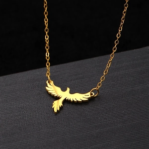 Close-up of a polished gold eagle pendant on a minimalist chain over a black jewelry box