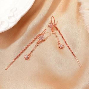 Macro detail of rose gold tassel earrings with star motifs and zircon inlay