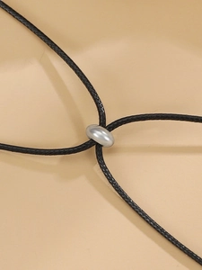 Close-up of black braided cord necklace with a polished silver oval metal slide clasp