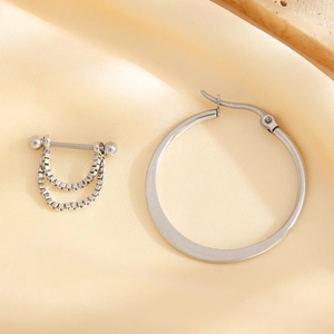Macro detail of stainless steel paperclip earring set on a beige silk background