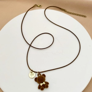 Dettaglio del ciondolo a forma di orsetto marrone con fiocco dorato e collana regolabile