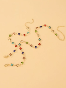 Détail d'un collier en chaîne dorée avec gemmes colorées en forme de cœur et fermoir