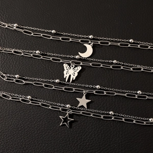Detail of silver double-layered chain bracelets featuring moon, butterfly and star charms