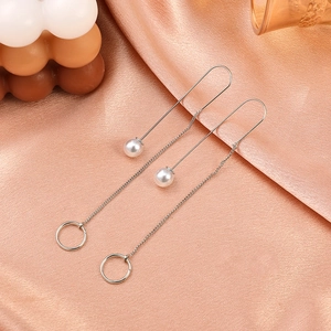Close-up of elegant silver tassel earrings with white pearls on rose gold silk fabric
