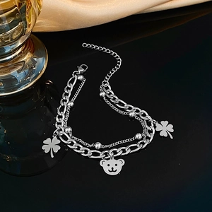 Close-up of double-layer silver chain bracelet with clover and bear charms on black silk