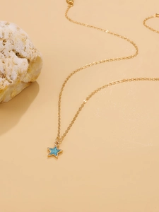 Detailed close-up of a gold star pendant necklace with blue enamel on beige background