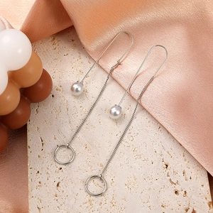 Detailed shot of long silver tassel earrings with U-shaped hooks and white pearls
