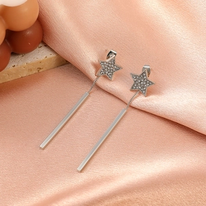 Detail view of silver star-shaped earrings with tassel drop on soft pink silk background