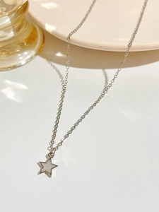Detail shot of a silver star pendant necklace on a minimalist ceramic display