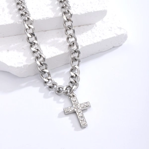 Detailed view of silver cross pendant with crystals on thick Cuban chain jewelry