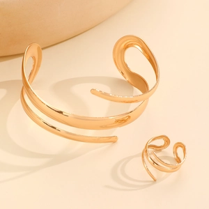 Close-up of a gold-plated irregular spiral bangle and ring set with a high-polished finish