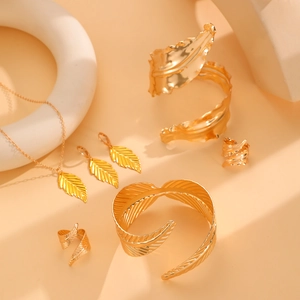Golden metal jewelry set with leaf texture including open bangles, rings and necklace