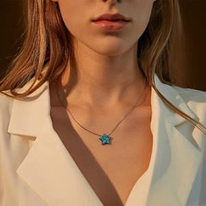 Close-up of star-shaped blue opal pendant necklace worn by a model in white