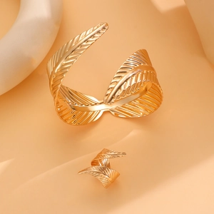 Macro detail of golden metal jewelry set showing leaf vein texture on ring and cuff