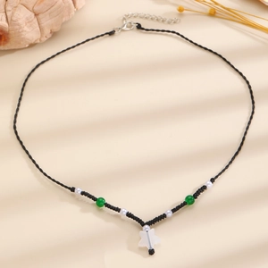 Detail of hand-woven black cord necklace with green beads and star pendant in soft lighting