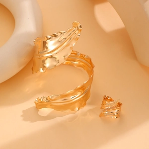 Detail of gold metal leaf jewelry set with intricate veins on upper arm cuff and ring