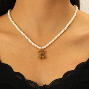 Dettaglio del ciondolo a forma di orsetto marrone su una collana di perle bianche