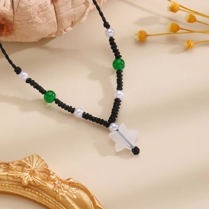 Detail of handcrafted star pendant necklace with white pearls and green beads on black cord