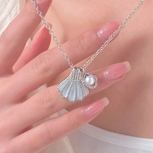 Detail view of a shell pendant necklace with a white pearl and silver-tone chain