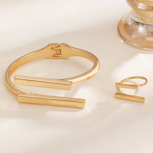 Detail of gold metal jewelry set featuring parallel bar cuff bracelet and open ring