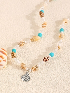 Close-up of shell and turquoise beaded necklace with a silver seashell pendant charm