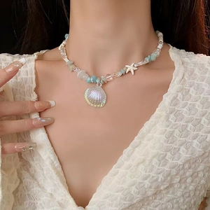 Detail of mermaid shell pearl necklace with blue beads and iridescent shell pendant