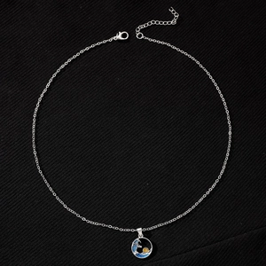 Detailed macro shot of a silver shell pearl necklace with blue enamel wave pendant