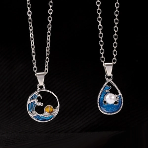 Macro detail of silver necklaces with sunset wave pattern and pearl teardrop pendant