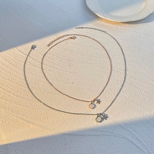 Detailed macro view of gold and silver clover necklaces with white shell and star charm