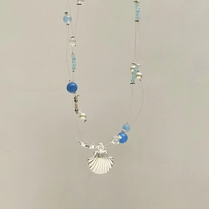 Detailed view of layered blue bead necklace with a silver seashell pendant and pearls