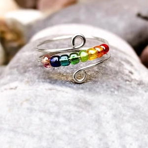 Detail of handmade wire wrapped fidget ring with seven colorful rainbow beads on natural stone