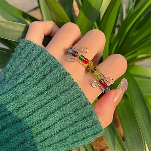 Detail of handmade wire wrapped rings with colorful beads shown on a model hand