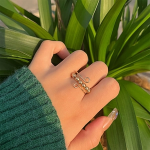 Adjustable gold anti-stress ring with five rotatable beads shown on a finger