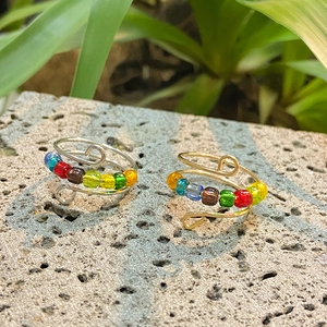 Detail of handmade wire wrapped fidget ring with colorful beads on a grey rock