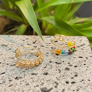 Detail of handmade gold wire spinner rings with colorful rainbow beads on stone