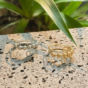 Close-up of adjustable fidget rings with rotating beads in silver and gold on a stone base