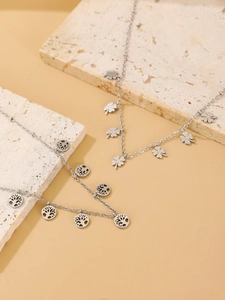 Detail of silver clover and tree of life pendants on polished stainless steel chains