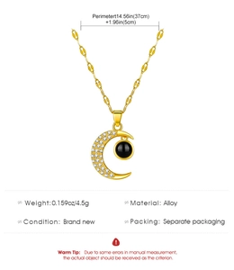 Detail of moon-shaped pendant with cubic zirconia and black bead on golden alloy chain