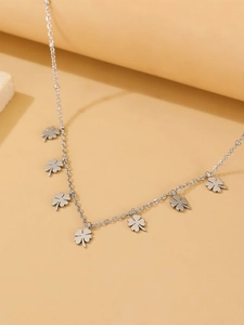 Detailed macro view of seven silver clover pendants on a minimalist stainless steel chain
